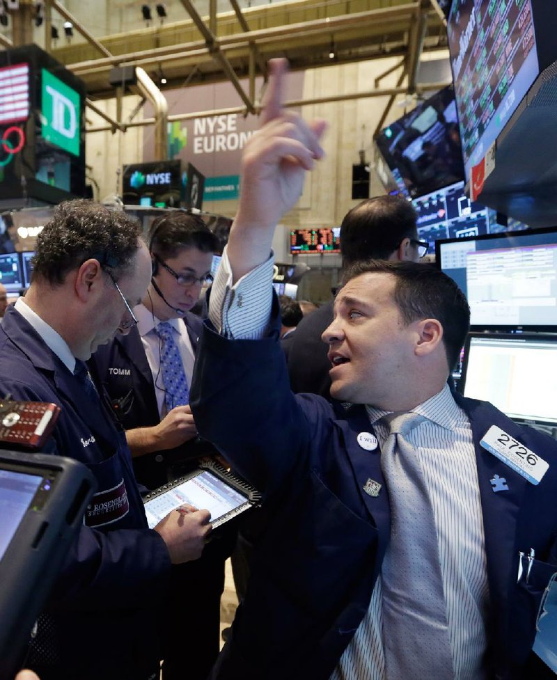 Specialist Paul Cosentino (right) works at his post Wednesday on the floor of the New York Stock Exchange. 