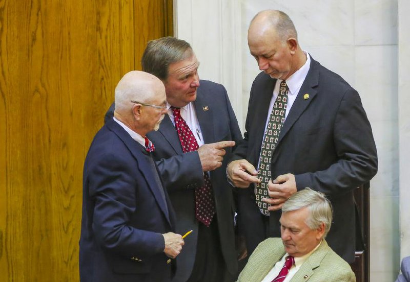 Republican state Reps. Les Carnine of Rogers (standing, from left), Lane Jean of Magnolia and Bruce Cozart of Hot Springs, along with Jonathan Barnett (seated) of Siloam Springs confer Thursday in the House chamber. 