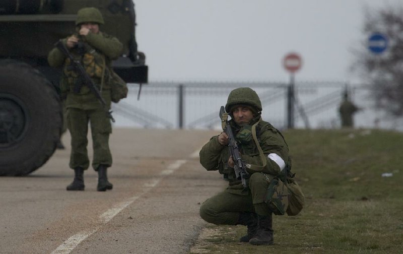 Amid reports of Russian military activity in the area Friday, unidentified soldiers block the road toward the military airport at the Black Sea port of Sevastopol in Ukraine’s Crimea region. 