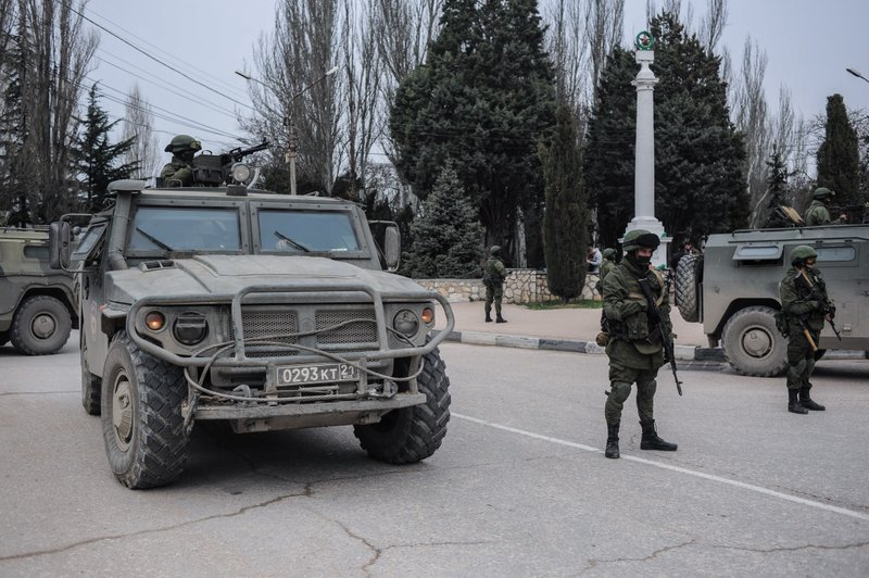 Troops in unmarked uniforms stand guard in Balaklava on the outskirts of Sevastopol, Ukraine, Saturday, March 1, 2014. An emblem on one of the vehicles and their number plates identify them as belonging to the Russian military. 