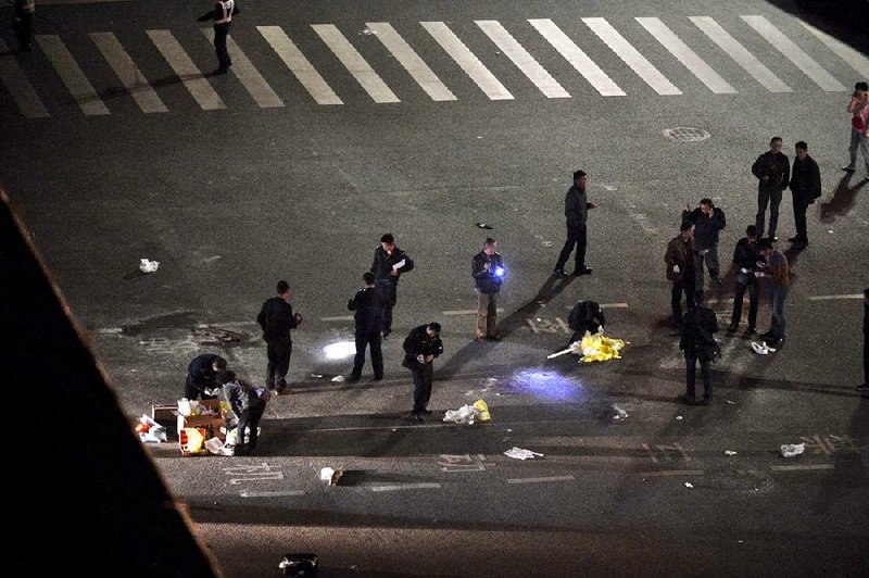 Police officers investigate the crime scene outside a railway station after an attack by knife wielding men leaving some 27 people dead in Kunming, in southwestern China's Yunnan province, Saturday March 1, 2014. China's official Xinhua News Agency says authorities consider the attack by a group of knife-wielding assailants at a train station in southwestern China in which at least 27 people died to be an act of terrorism. (AP Photo)  CHINA OUT