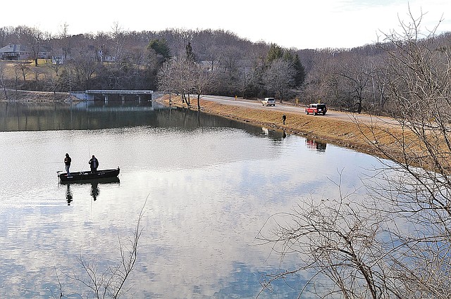 STAFF PHOTO FLIP PUTTHOFF Visitors to Lake Atalanta on water and land are seen on Thursday afternoon near the dam in Rogers.