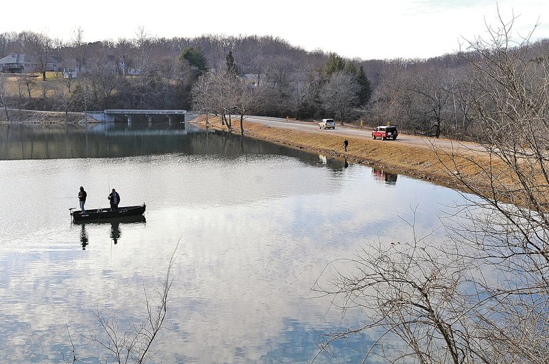 STAFF PHOTO FLIP PUTTHOFF Visitors to Lake Atalanta on water and land are seen on Thursday afternoon near the dam in Rogers.