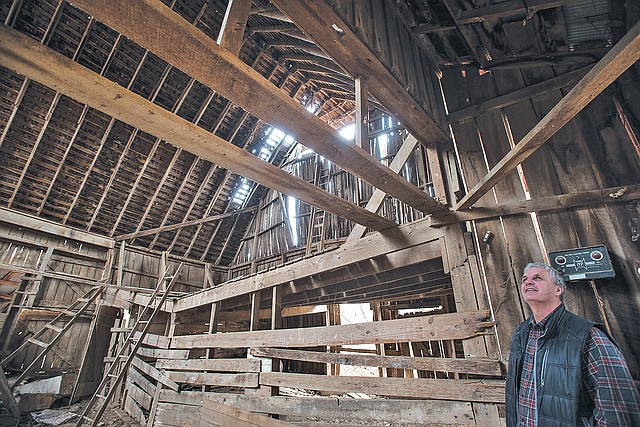 STAFF PHOTO ANTHONY REYES Sprouse looks around the inside of a barn Friday at the Rabbits Foot Lodge in Springdale. The barn is old and some think it may be one of the oldest in the state.