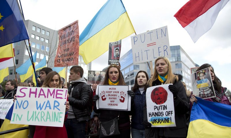 Pro-Ukrainian demonstrators hold signs during a protest outside of an emergency meeting of EU foreign ministers at the EU Council building in Brussels on Monday, March 3, 2014. EU foreign ministers meet in emergency session Monday to discuss the ongoing crisis in Ukraine.