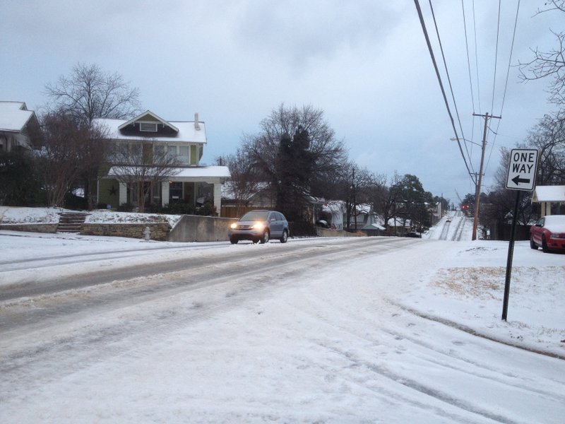 A vehicle moves along an icy Markham Street in Little Rock Monday morning.