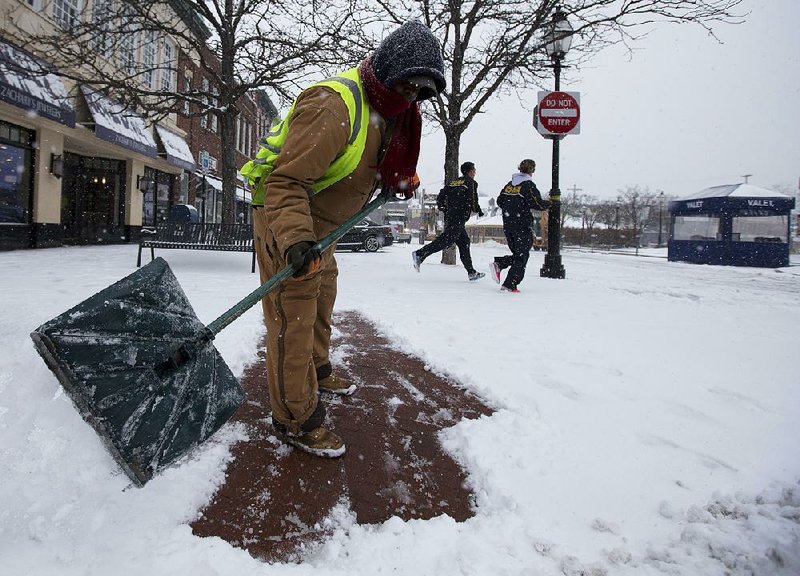 Annapolis, Md. city worker Harold Clark shovels snow from a sidewalk as snow continues to fall in Annapolis, Md., Monday, March 3, 2014. Spring is in sight, but winter is keeping its icy hold on much of the country, with up to a foot of snow and plummeting temperatures expected across the Mid-Atlantic states and up the East Coast.  (AP Photo/Carolyn Kaster)