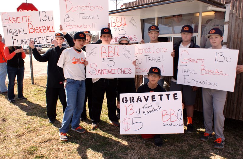 Photo by Dodie Evans Members of the Gravette (13U) summer baseball team and their sponsors were busy on a recent Saturday trying to attract motorists to stop and buy barbecue sandwiches they were selling at a location in Centennial Park in Gravette. Funds will help pay transportation costs when the team travels to out-of-town games later this spring. Several of the boys are shown with the signs which they displayed at the intersection of Highways 59 and 72.