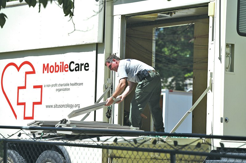 FILE PHOTO ANTHONY REYES An FBI agent unloads pieces of shelves June 27 while searching motor coaches and Situs Cancer Research Center in Rogers. Jim Bolt, 60, pleaded guilty to one count of wire fraud, one count of mail fraud and one count of money laundering in a plea bargain with prosecutors.