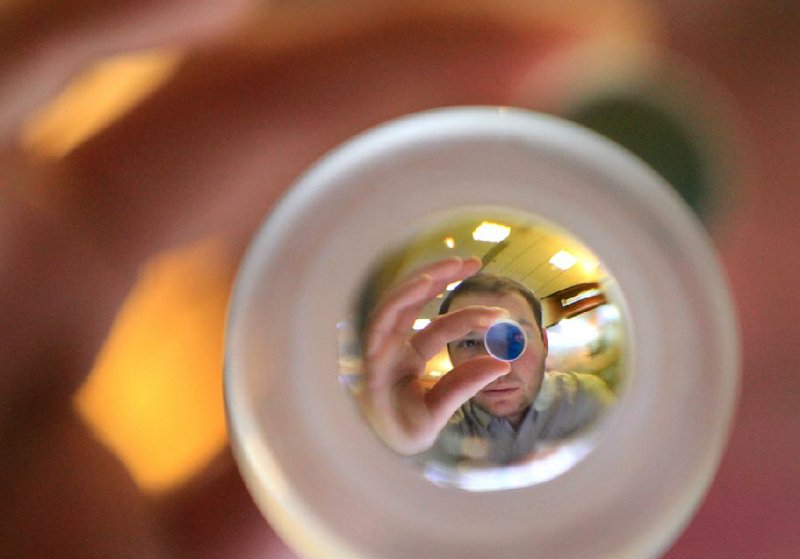 Brett Boister, a sales engineer at Power Technology Inc., demonstrates an optical lens used in laser models at the Arkansas Aerospace Summit Wednesday. The two-day event ends today. 