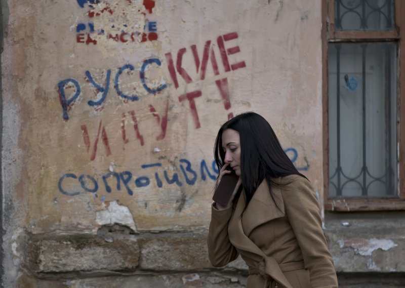 A woman passes by a graffiti that reads "The Russians are coming - Resistance" in Simferopol, Ukraine, on Friday, March 7, 2014. Ukraine lurched toward breakup Thursday as lawmakers in Crimea unanimously declared they wanted to join Russia and would put the decision to voters in 10 days.