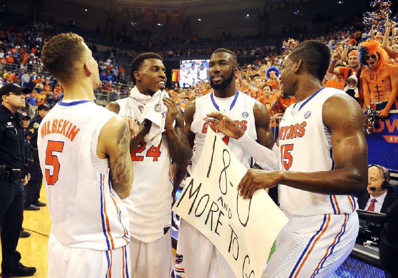 Florida players (from left) Scottie Wilbekin, Casey Prather, Patric Young and Will Yeguete celebrate the Gators’ perfect SEC record after defeating No. 25 Kentucky 84-65 on Saturday. 