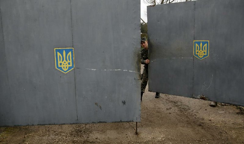 A Ukrainian soldier shuts a gate Saturday at a military base in Sevastopol in the Crimean region that was stormed Friday by soldiers who a Ukrainian officer said were clearly Russian. 