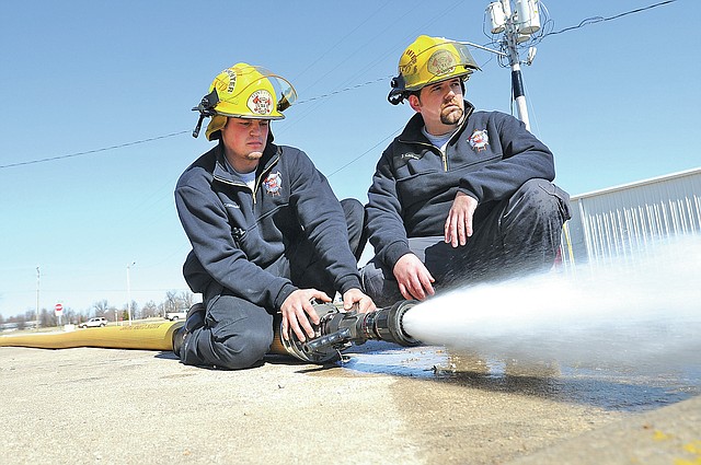 FILE PHOTO ANTHONY REYES Derek Crutchfield, left, and Josh Latham, both Tontitown firefighters, test a five-inch hose Feb. 19, 2013, at the Tontitown fire station. Tontitown&#8217;s City Council approved last week replacing the Police Department with a Department of Public Safety. The council also wants to add the Tontitown Fire Department to the new department.