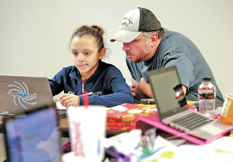 STAFF PHOTO JASON IVESTER Alyssa Alberson, 10, gets a hand Thursdsay from her father, Thomas Alberson, while working on her online school work.