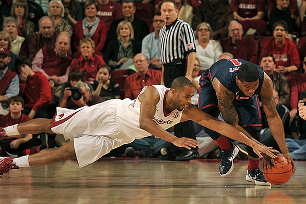 Arkansas guard Rickey Scott Jr. and Ole Miss guard Martavious Newby dive after the ball during the first half of Wednesday night's game at Bud Walton Arena in Fayetteville.