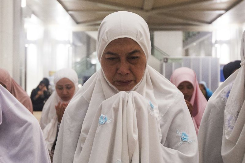 A Malaysian Muslim woman offers a special prayer for passengers aboard a missing plane, at a mosque in Putrajaya, Malaysia, Sunday, March 9, 2014. Military radar indicates that the missing Boeing 777 jet may have turned back before vanishing, Malaysia's air force chief said Sunday as authorities were investigating up to four passengers with suspicious identifications. (AP Photo/Joshua Paul)