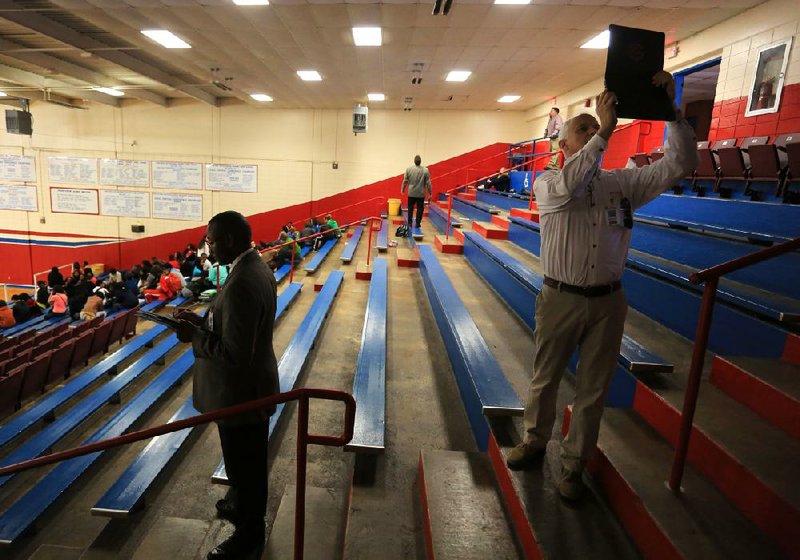 Troy Glover (left), a planner with Fanning-Howey, an architecture and engineering firm, and Rodgers Critz (right), an architect with Stuck Associates Architects, evaluate the structure and facilities of the gym at Parkview High School in Little Rock. 