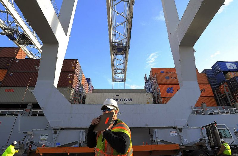 A dock worker shields his radio with a clipboard while a crane loads containers onto a ship at the Georgia Ports Authority Garden City terminal in Savannah in January. Wholesalers increased stockpiles 0.6 percent in January from December, the Commerce Department said Tuesday. 