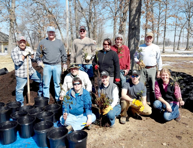 Photo by Randy Moll Planting trees in pots on Thursday to be placed at the SWEPCO tree farm at the Flint Creek Power Plant for planting in the fall were Rita Whiting (front, left), Delia Haak, Ethan Whiting, Lauren Ray, Tim Snell (squatting behind the front row), Terry Stanfill (back, left), Ralph Weber, Scott Carney, Becky Roark, Cody Haak and Rex Barrett.