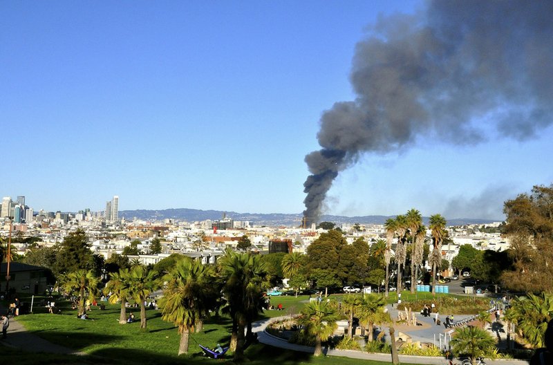 In this photo released by Danielle Gasbarro, smoke rises from a fire as seen from Dolores Park in San Francisco  on Tuesday, March 11, 2014. San Francisco firefighters have prevented a major blaze from spreading from a condominium construction site to nearby buildings. 