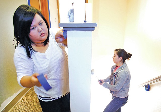 STAFF PHOTO DAVID GOTTSCHALK Maxine Phansiri, left, of Lowell tapes a banister as Kourtney Connell of Bentonville rolls paint Wednesday at the Seven Hills Walker Family Residential Community in Fayetteville. Phansiri and Connell were volunteers from Walmart's Global Emergency Management team participating in the United Way's Live United Day.