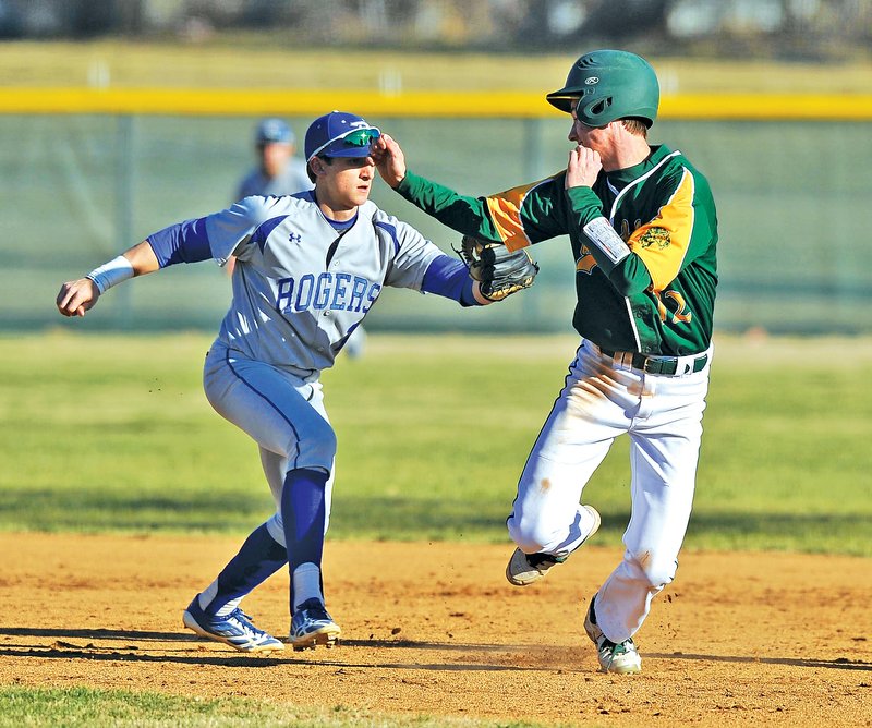 Staff Photo Michael Woods • @NWAMICHAELW Timmy Seldomridge, Rogers High short stop, tags Alma baserunner Adam Wilbanks on Wednesday as Wilbanks gets caught in a rundown between first and second base at Veterans Park in Rogers.