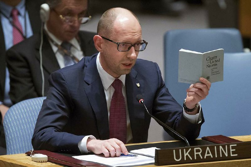 Ukrainian interim Prime Minister Arseniy Yatsenyuk speaks as he holds a copy of the United Nations charter during an U.N. Security Council meeting on the Ukraine crisis, Thursday, March 13, 2014, at the United Nations Headquarters. Yatsenyuk, during a meeting with President Barack Obama on Wednesday, declared in English that his government was "absolutely ready and open for talks with the Russian Federation" and urged Moscow to "start the dialogue" without guns and tanks. (AP Photo/John Minchillo)