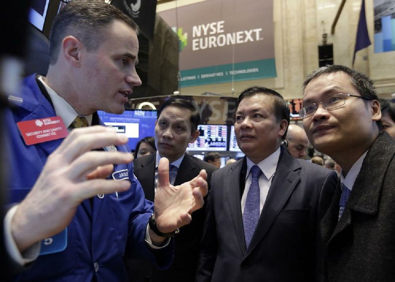 Vietnam's Finance Minister Dinh Tien Dung, second from right, visits the trading post of specialist Jason Hardzewicz on the floor of the New York Stock Exchange, Thursday, March 13, 2014. Stocks opened higher as traders were encouraged by a pickup in retail sales and more signs of health in the U.S. job market. (AP Photo/Richard Drew)