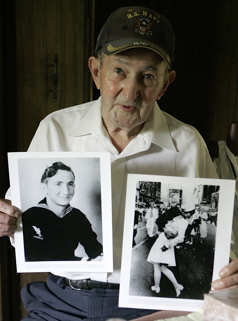 FILE - In this July 31, 2007 file photo, Glenn McDuffie holds a portrait of himself as a young man, left, and a copy of Alfred Eisenstaedt's iconic Life magazine shot of a sailor, who McDuffie claims is him, embracing a nurse in a white uniform in New York's Times Square, at his Houston home. McDuffie, who became known for claiming he was the sailor kissing a woman in Times Square in a famous World War II-era photo taken by a Life magazine photographer has died. Houston Police Department forensic artist Lois Gibson, who says she identified McDuffie as the man in the picture, says Friday, March 14, 2014 that he died March 9. McDuffie was 86.