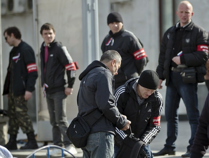 Members of the Crimean self defense forces check a passenger at the main railway station in Simferopol, Ukraine, Friday, March 14, 2014. Members of the Crimean self defense forces check the luggage and identity documents of passengers arriving by train, especially from western Ukrainian cities or the capital, to Simferopol, looking for what they label as provocateurs, ahead of the March 16 referendum that will ask residents if they want the territory to become part of Russia.
