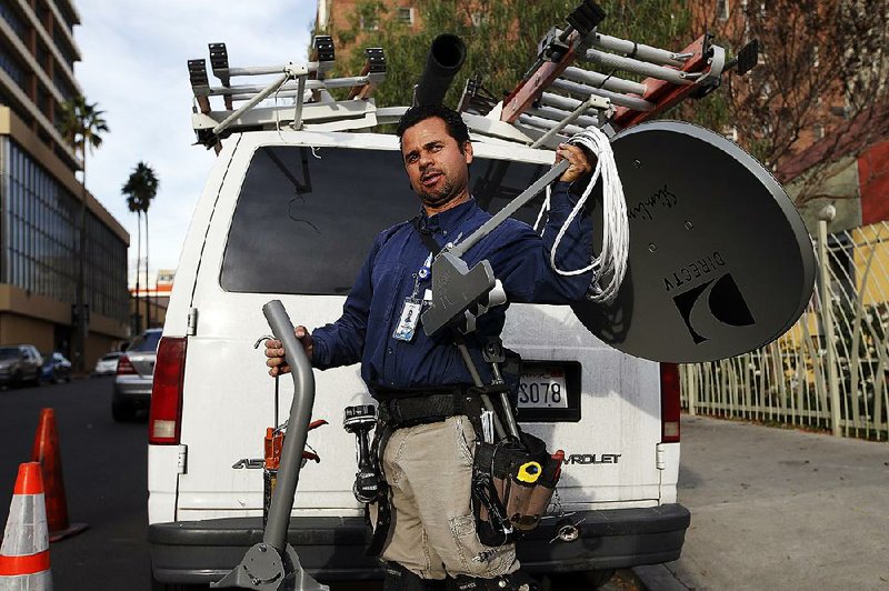 Cesar Ramirez, a subcontractor for DirecTV, gets ready to install a DirecTV satellite dish in Los Angeles, Tuesday, Jan. 22, 2013. Contract workers, consultants, freelancers or the self-employed face additional challenges at tax-filing time. (AP Photo/Jae C. Hong)