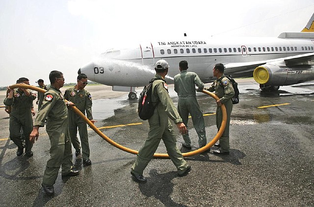 Crew members spray water at an Indonesian Air Force Boeing 737 "Surveiller" of the 5th Air Squadron "Black Mermaids" to wash sea water off its fuselage after a low altitude flight to search for the missing Malaysia Airlines Boeing 777 over the Strait of Malacca, at Suwondo air base in Medan, North Sumatra, Indonesia, Friday, March 14, 2014. The jetliner vanished nearly a week ago with 239 people aboard. (AP Photo/Binsar Bakkara)