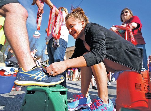 FILE PHOTO JASON IVESTER Jennifer Mosley of Fayetteville clips a timing tag from a runner&#8217;s shoe April 14 after finishing the Hogeye Marathon in Fayetteville.