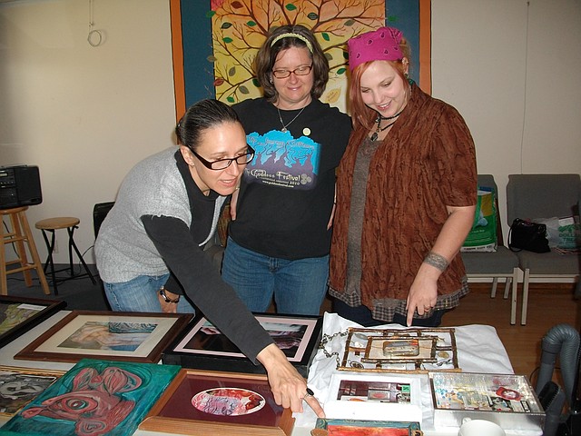 Staff Photo Becca Martin-Brown Krystina Poludnikiewicz, from left, Julie Jeannene and Cat Oswald look at entries for this year&#8217;s Goddess Festival art show. The festival begins Sunday at the Omni Center for Peace, Justice &amp; Ecology in Fayetteville.