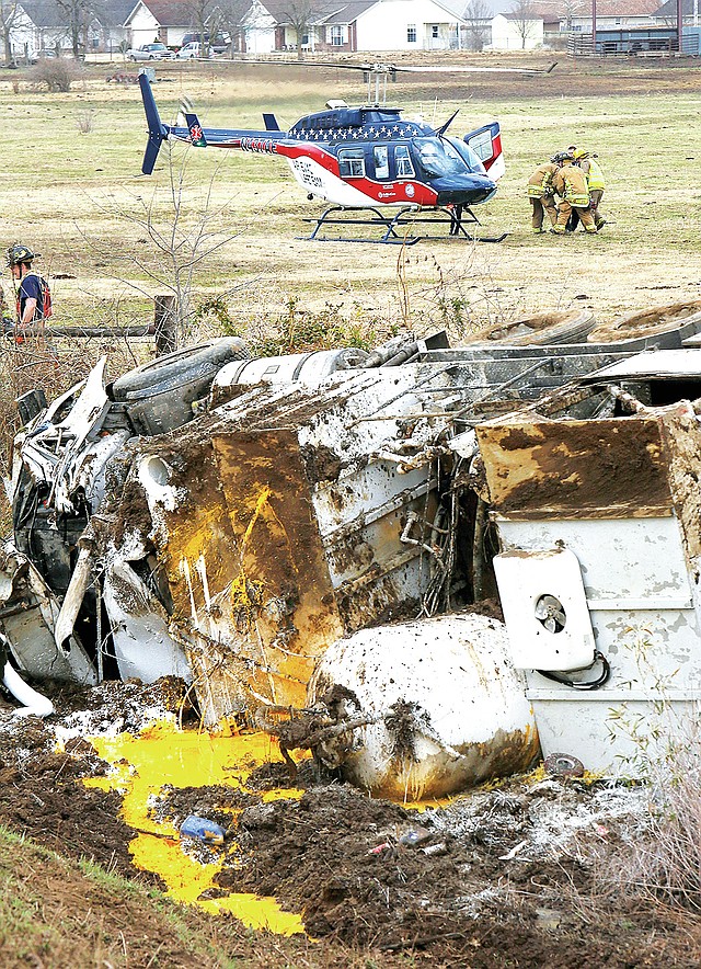 STAFF PHOTO DAVID GOTTSCHALK Emergency personnel carry Terry Moore Friday to an awaiting helicopter for evacuation following a one-truck accident around 10:50 a.m. on Arkansas 16 between Elkins and Fayetteville.