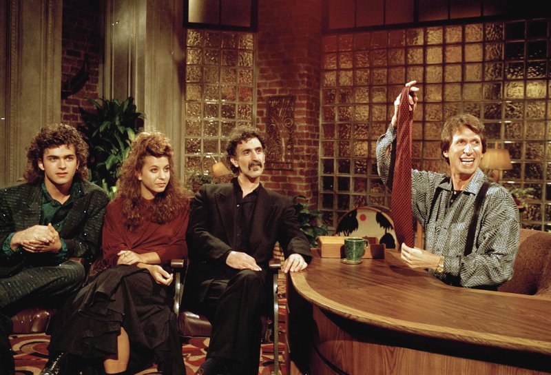 FILE - In this Sept. 24, 1986 file photo, comedian David Brenner hosts avant garde fusion musician Frank Zappa, center, and his children, Dweezil, left, and Moon Unit, during a taping of Brenner's "Nightlife" talk show in New York. Brenner holds a necktie given to Frank Zappa upon entering a restaurant earlier in the day. On Saturday, March 15, 2014, publicist Jeff Abraham announced Brenner has died at the age of 78. 