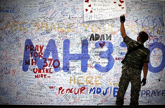 A Malaysian military soldier patrols the viewing gallery of the Kuala Lumpur International Airport where dedication boards with well wishes and messages for people involved with the missing Malaysia Airlines jetliner MH370 is displayed, Sunday, March 16, 2014 in Sepang, Malaysia. Malaysian authorities Sunday were investigating the pilots of the missing jetliner after it was established that whoever flew off with the Boeing 777 had intimate knowledge of the cockpit and knew how to avoid detection when navigating around Asia. (AP Photo/Wong Maye-E)