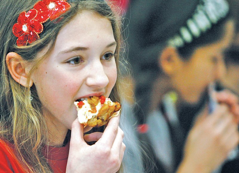 STAFF PHOTO DAVID GOTTSCHALK Grace Martin, 12, a Holt Middle School sixth-grader, tries a piece of barbecue chicken and vegetable pizza during a tasting at lunch Monday at the school in Fayetteville. Members of the student council served samples to fellow students as part of a project allowing students to sample and vote on possible new healthy menu items.