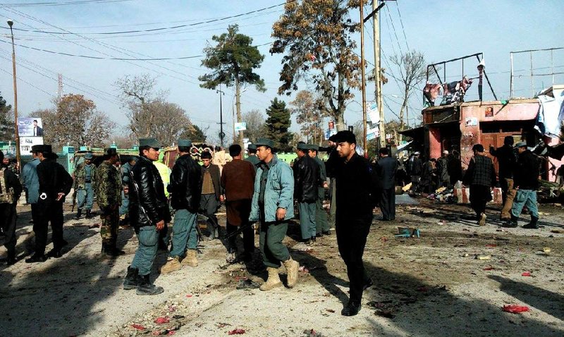 Afghan police officers and civilians inspect the site of a suicide attack in Maymana, Afghanistan, on Tuesday. 