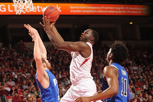 Arkansas forward Alandise Harris , center, reaches to score past Indiana State forward Justin Gant, left, during the second half Tuesday, March 18, 2014, at Bud Walton Arena in Fayetteville.