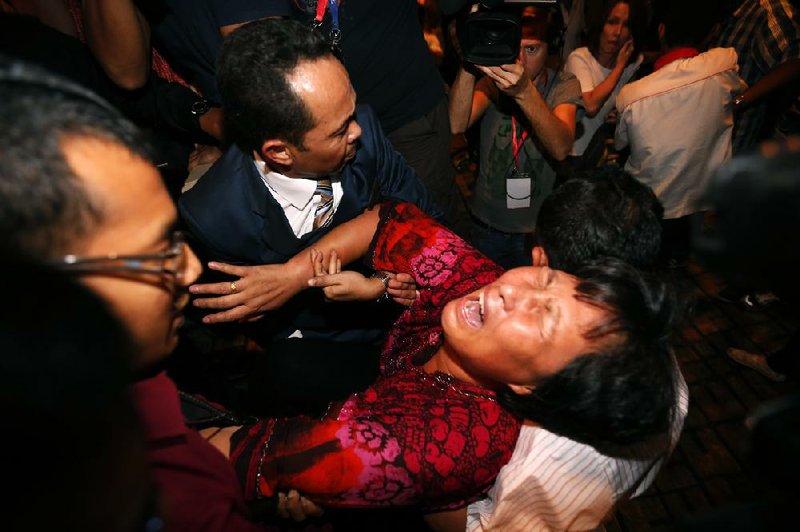 A Chinese relative of a passenger aboard the missing Malaysia Airlines plane is carried out by security officials as she protests Wednesday before a news conference in Sepang, Malaysia. 