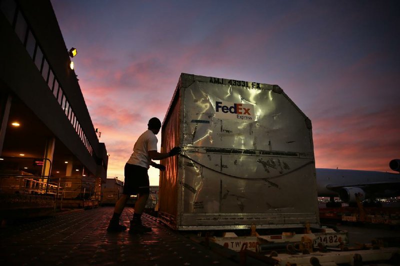 A FedEx Corp. employee prepares to load a container onto a FedEx plane at Los Angeles International Airport in this file photo. The company said shipments dropped off this winter because snow and ice closed some retail shippers in the East and Midwest. 