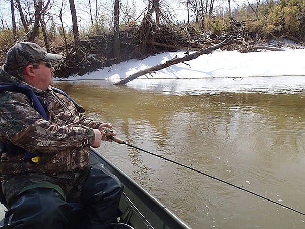 STAFF PHOTO FLIP PUTTHOFF 
Ron Duncan looks at a snow-covered shoreline and cold, muddy water while floating on March 7 down the War Eagle River. A spell of warm weather had the snow melting and the river rising on a sun-splashed Friday.