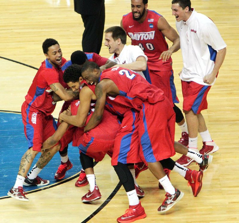Dayton players celebrate (above) on the floor after a 60-59 victory over Ohio State on Thursday in the first round of the NCAA Tournament’s South Region in Buffalo, N.Y. The Flyers survived a last-second shot by the Buckeyes for the victory. Dayton advances to meet Syracuse on Saturday.