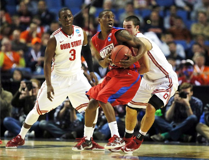 Dayton’s Jordan Sibert (center) spins past Ohio State’s Aaron Craft (right) during the second half of Thursday’s NCAA Tournament second-round game in Buffalo, N.Y. The Flyers upset the sixth-seeded Buckeyes, winning 60-59. 