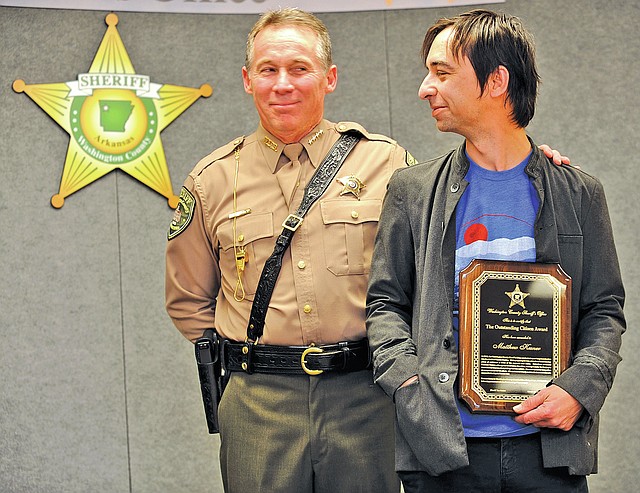 STAFF PHOTO ANDY SHUPE Sheriff Tim Helder, left, smiles with Matthew Kesner on Thursday as Kesner is awarded the Outstanding Citizen Award during the annual Washington County Sheriff&#8217;s Office Awards and Promotional Ceremony in Fayetteville. Kesner assisted the Sheriff&#8217;s Office by enhancing video taken at a crime scene.