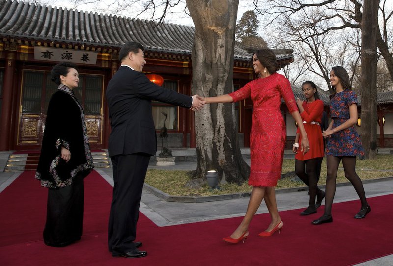 U.S. first lady Michelle Obama, third from right, her daughters Malia, right, and Sasha, second from right, is greeted by Chinese President Xi Jinping, second from left, and his wife Peng Liyuan, left, at the Diaoyutai State guest house in Beijing, China Friday, March 21, 2014. U.S. first lady Michelle Obama met with excited students who were building robots and tried her hand at Chinese calligraphy Friday during a tour of a Beijing high school. 
