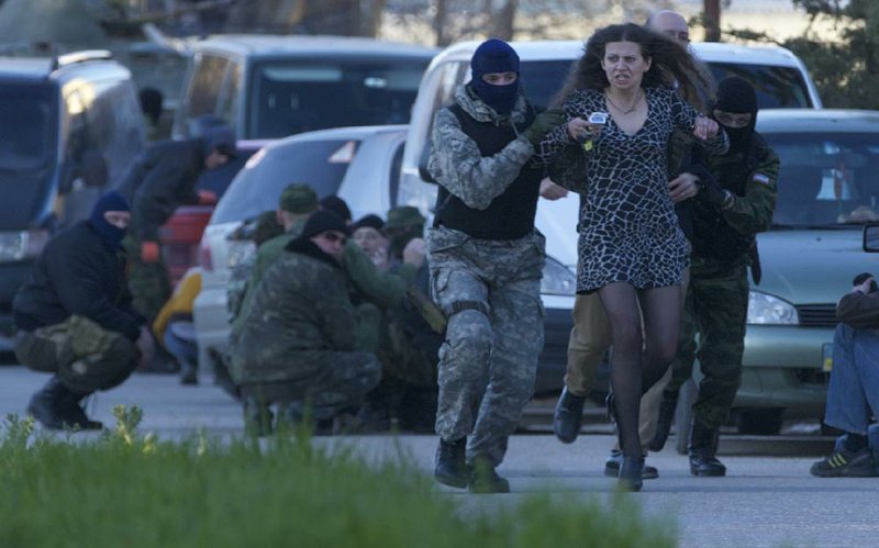 Pro-Russian militia members evacuate a woman Saturday from near the Belbek military base outside Sevastopol in Crimea, as Russian troops moved in to take over the facility. 