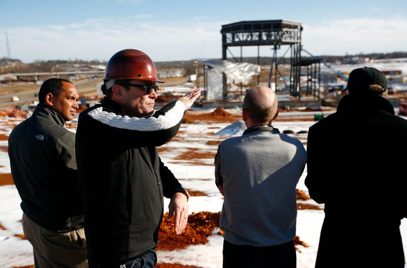 FILE PHOTO &#8212; Project manager David Swain, second from left, details progress as crews continue construction on the Walmart Arkansas Music Pavilion on Feb. 11 at its new location in Rogers. The 7,000-seat performance space provides a permanent home for the AMP.